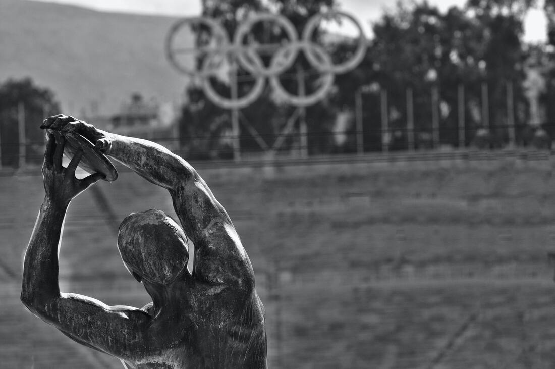 statue of an athlete with Olympic rings in the background