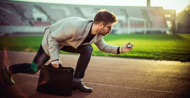 Guy in a suit on a track getting ready to run