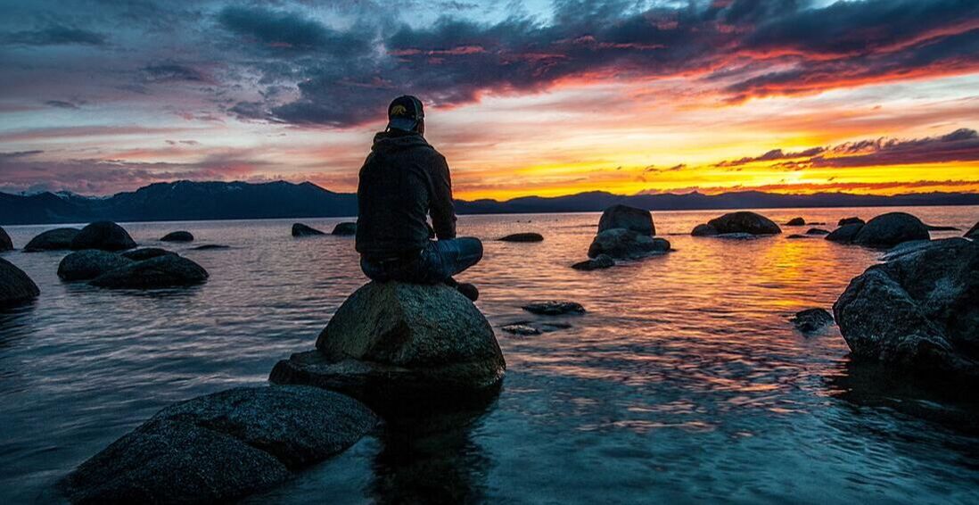 Man sitting on a rock staring into the sunset