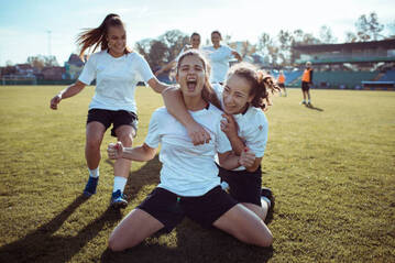 Girls playing soccer celebrating