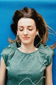 woman laying on her back with earbuds in