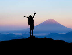 Woman raising her hands on mountain peak